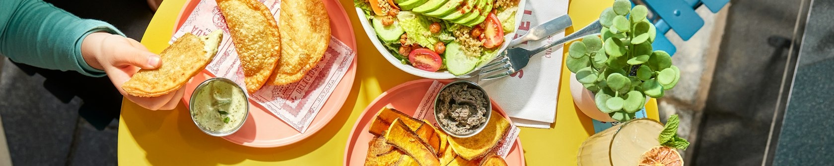 A bright and inviting table with empanadas, plantain chips and a fresh salad.