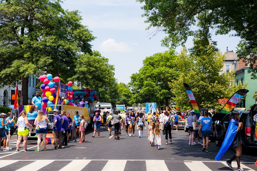 A busy neighborhood street filled with people celebrating Pride. 