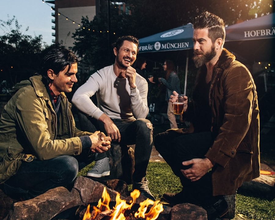 Friends gather around a fire.