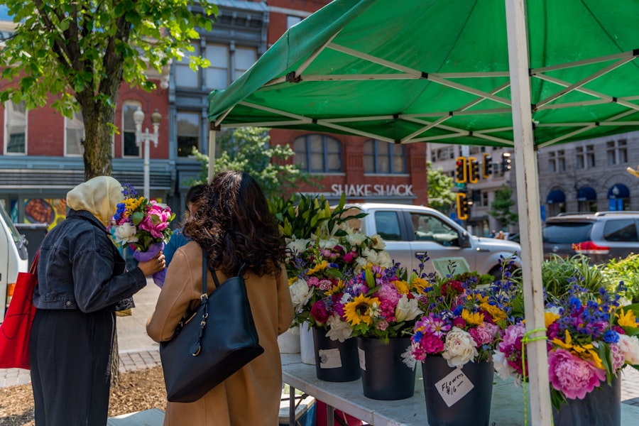 People browsing colorful bouquets at an outdoor flower stall in Penn Quarter.