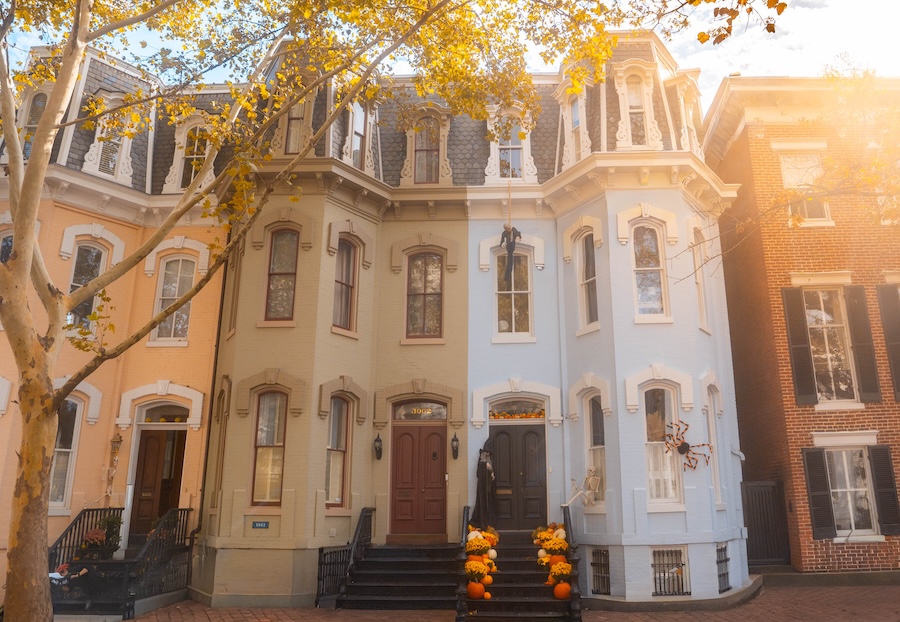 Colorful townhomes in Georgetown in the fall with Halloween decorations adorning the door in the center.
