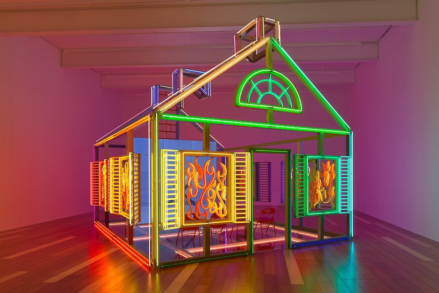 Alex Da Corte’s neon sculpture “Rubber Pencil Devil (Hell House)” glows in vibrant colors, shaped like a house with flames in the windows.