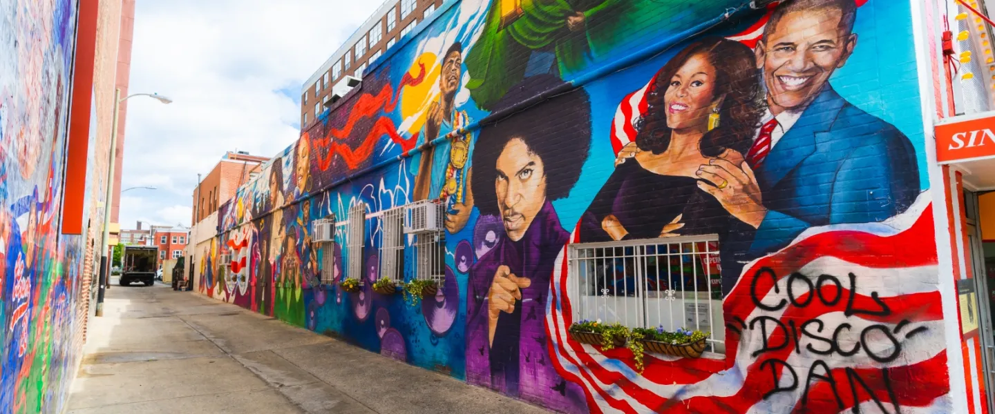 Colorful mural in Washington, DC alleyway featuring portraits of Barack and Michelle Obama, Prince, and other cultural icons.