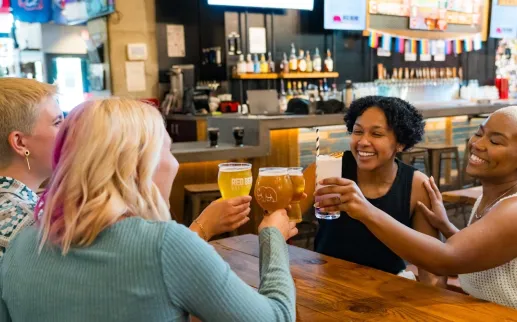 Four smiling people cheers in a cozy brewery. 