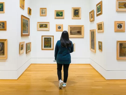  A visitor explores a gallery at The Phillips Collection, where small framed paintings in various styles are arranged on white walls, creating an immersive art experience.