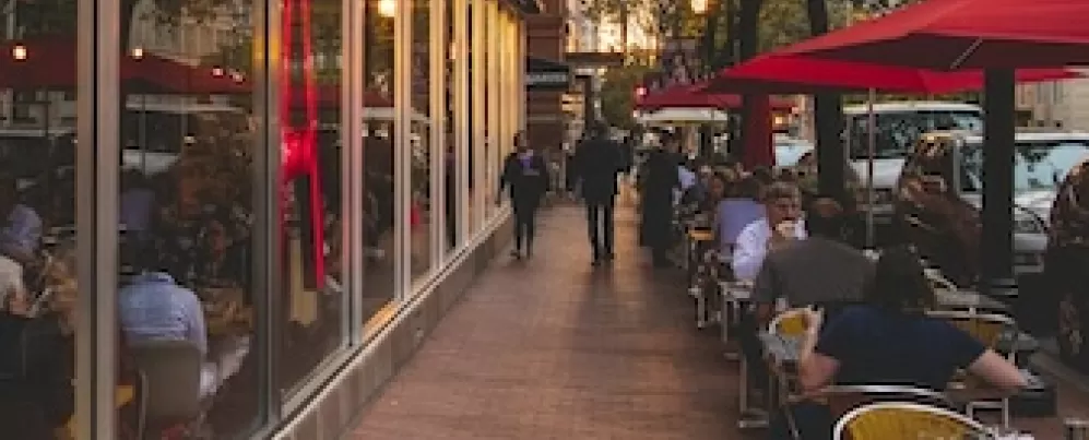 The exterior of Jaleo by José Andrés in Washington, DC, with large red neon lettering and outdoor seating under red umbrellas.
